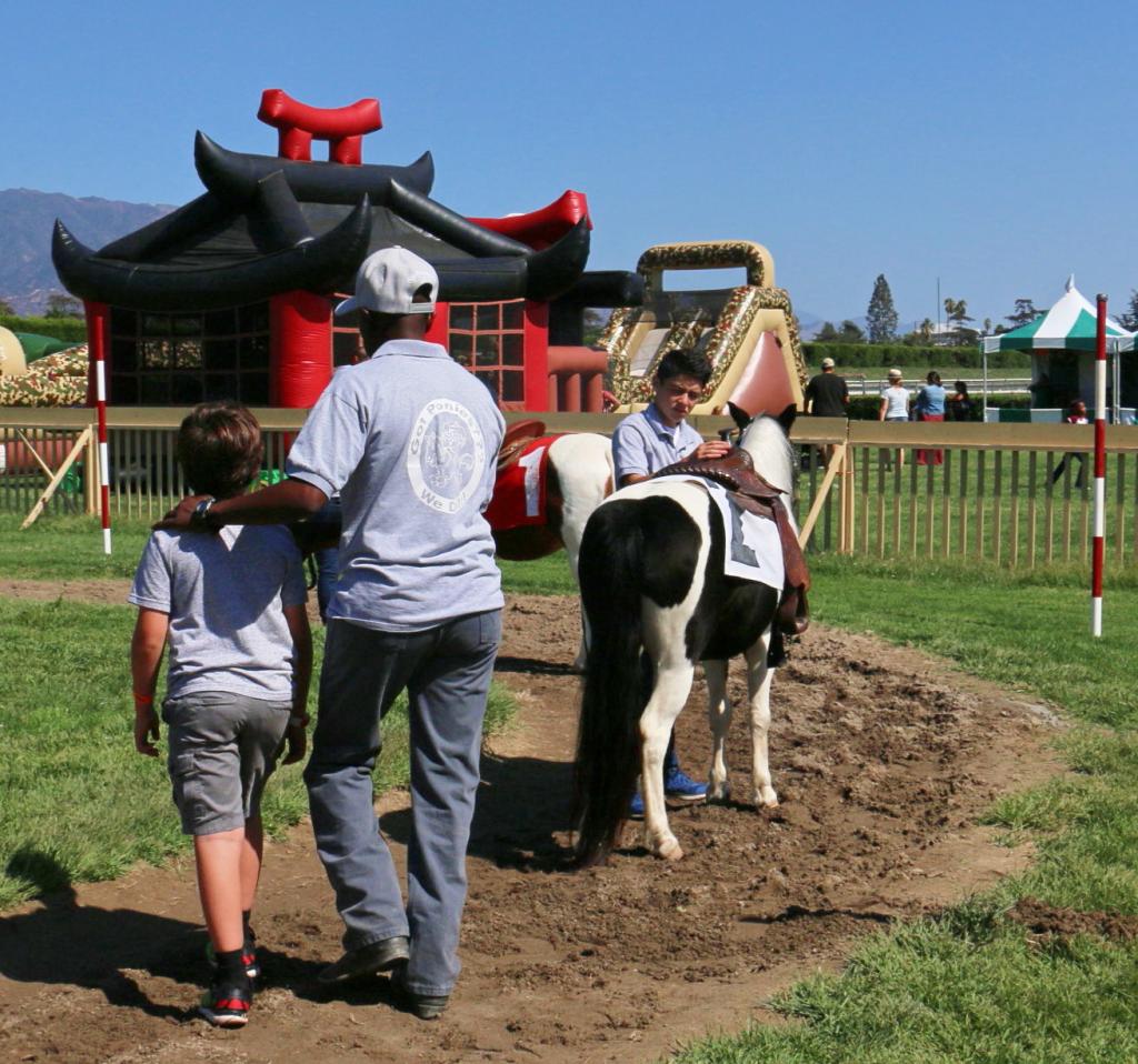 Gladney walking a child to a waiting pony in the Santa Anita infield. (Julie June Stewart photo)